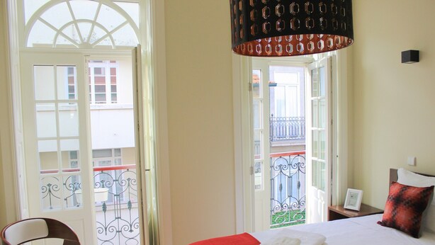 Una habitación de hotel con una cama, una silla y vistas al balcón exterior.