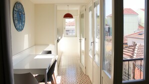 Un pasillo estrecho con una puerta blanca al final, una lámpara colgante roja y un reloj en la pared.
