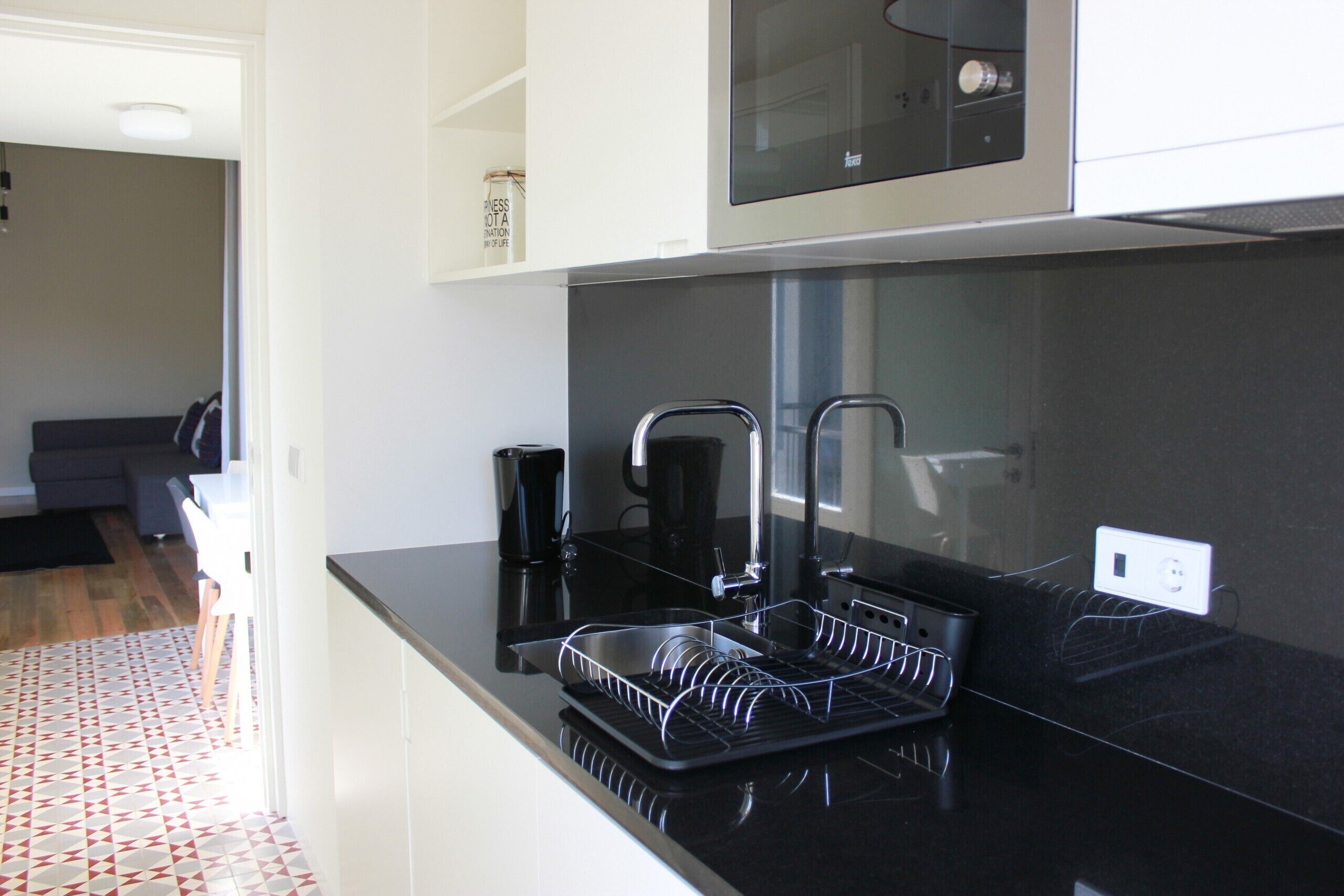 A modern kitchen with black countertops, stainless steel appliances, and a dish rack.