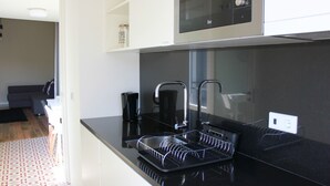 Una cocina moderna con encimeras negras, electrodomésticos de acero inoxidable y un escurreplatos.