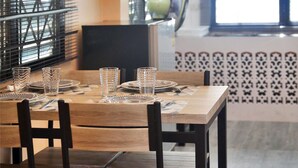 A dining area with a wooden table set for four, black chairs, and a patterned wall. - Villa Kamala Beach (Kamala)