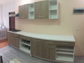 A kitchen with a built-in stove, wooden cabinets, and a white countertop. - Villa Kamala Beach (Kamala)