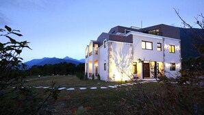A modern two-story house with a stone facade, large windows, and a well-lit entrance. - B&B Mountain View (Xincheng)