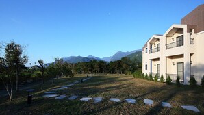 A modern hotel with a well-maintained lawn, stone pathway, and mountain views. - B&B Mountain View (Xincheng)