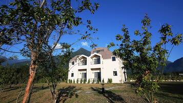 Set amidst lush greenery and a mountain range, this modern building offers a serene retreat.