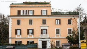 A two-story building with a symmetrical facade, a central entrance with a decorative pediment, and a small balcony above the ground floor. - La Chiostrina (Rome)