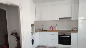 A modern kitchen with white cabinets, a built-in oven, and a washing machine. - T1 - Sea View Balcony (Armação de Pêra)