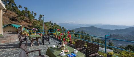 Una terraza con mesas dispuestas para comer, con vistas a un paisaje montañoso.