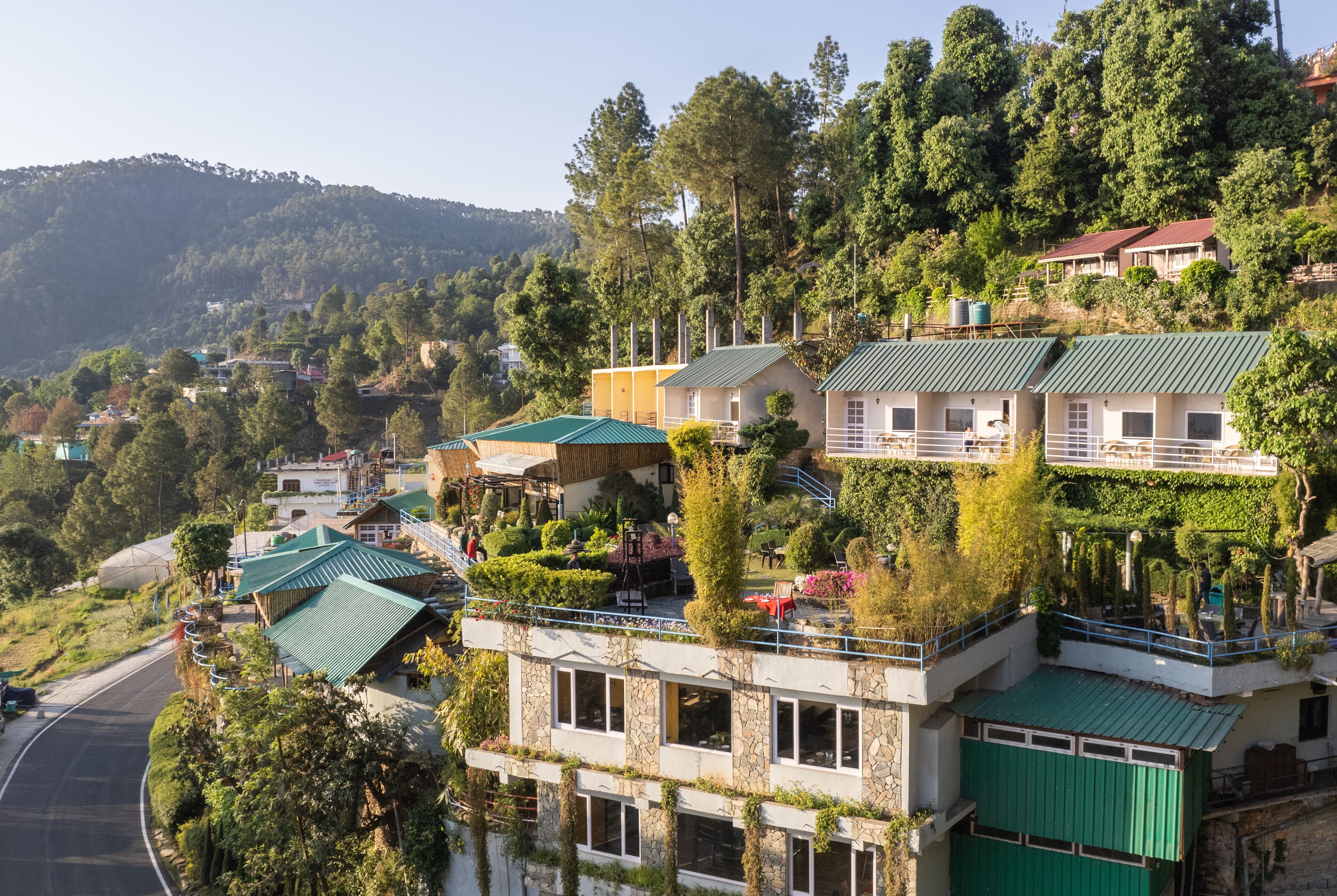 Un hotel en una ladera con varias edificaciones, cada una con techo verde y rodeada de abundante vegetación.