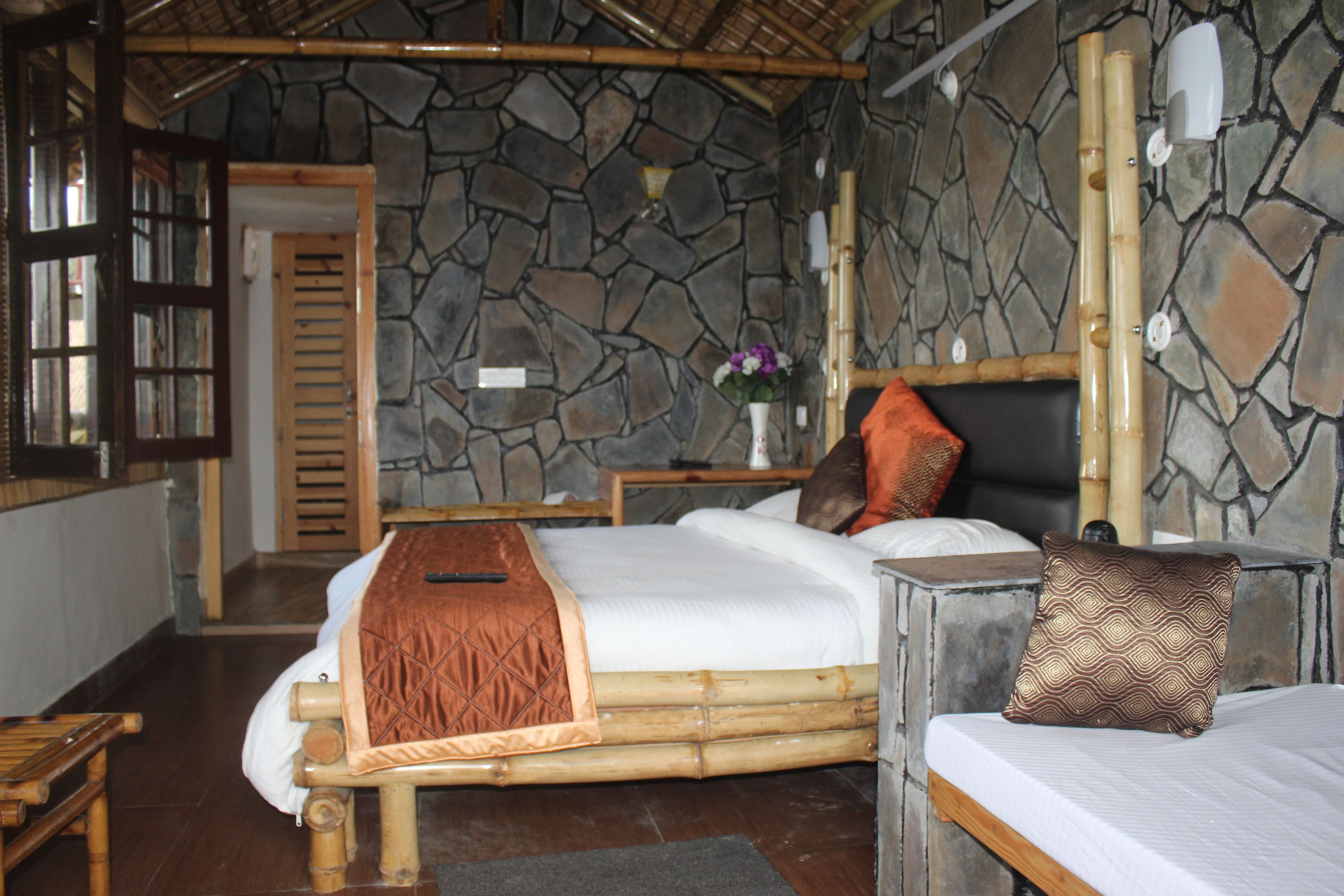 Una habitación con pared de piedra, una cama con cabecera, una mesita de noche y una ventana con vistas.