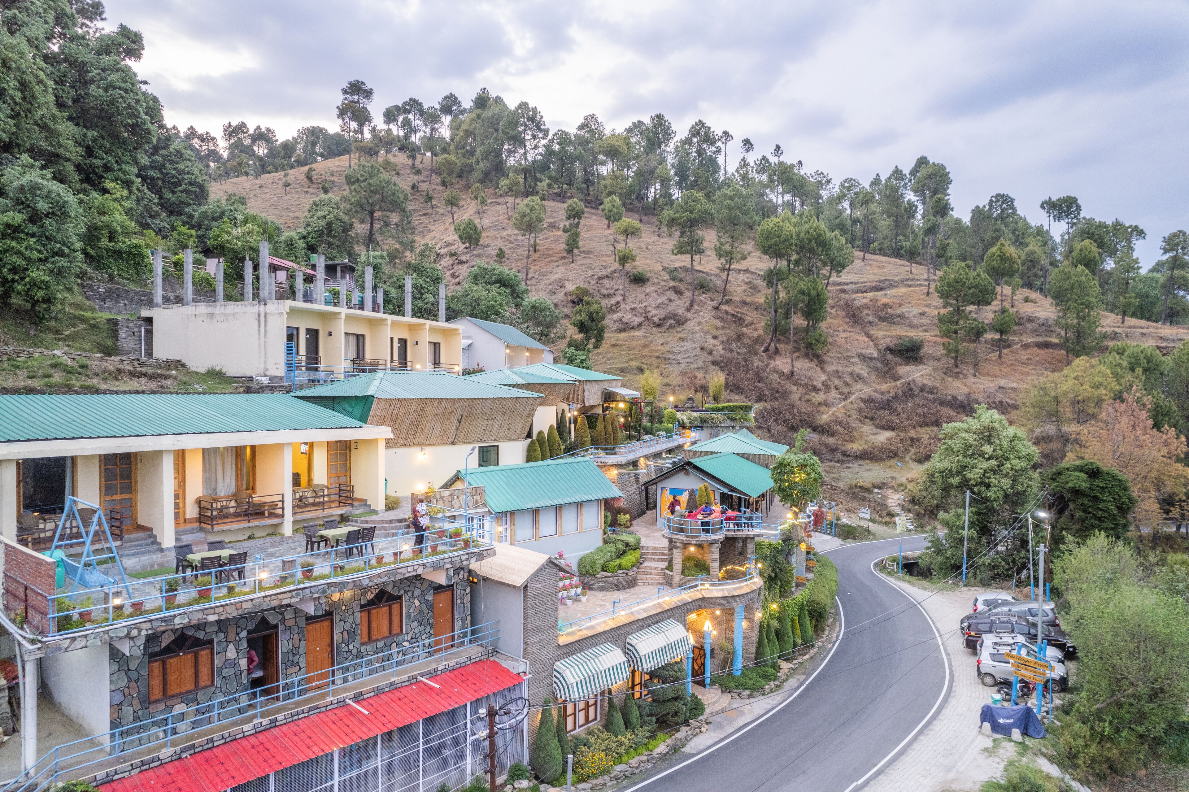 A hillside hotel with multiple buildings, a curved road, and a parking area.