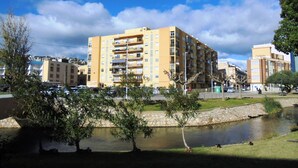 A multi-story residential building with balconies, a small pond, and surrounding greenery. - Los Labradores (Peñiscola)
