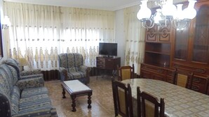 A living room with a sofa set, a dining table with chairs, a television, and a chandelier. - Los Labradores (Peñiscola)