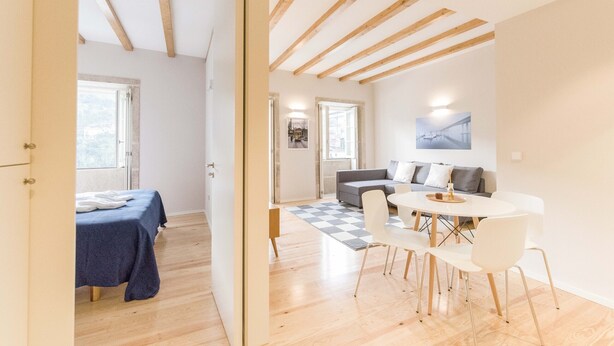 A modern living room with a sofa, a dining table with chairs, and a checkered rug. - Freixo - River View Apartment (Oporto)