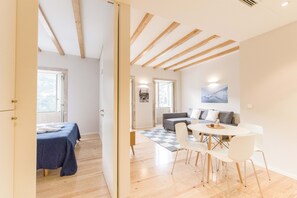A modern living room with a sofa, a dining table with chairs, and a checkered rug. - Freixo - River View Apartment (Oporto)