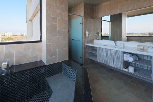 Un baño moderno con un espejo grande, una bañera y un tocador con toallas.