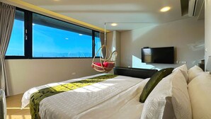 Habitación de hotel con una cama grande, una silla colgante, un televisor y una ventana con vistas a un puente.