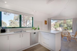 A modern kitchen with white cabinets, a dishwasher, and a large window.