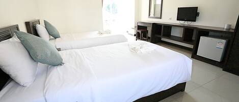Habitación de hotel con dos camas, un escritorio, un televisor y un refrigerador.