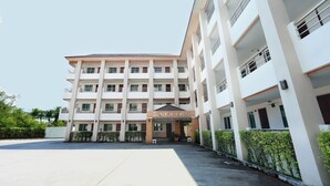 A multi-story hotel with a central entrance, balconies on each floor, and a parking area in front. - Weerawan Place (Khon Kaen)