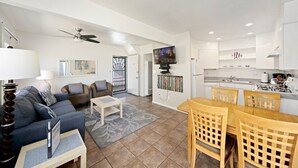 A spacious living area with a sofa, chairs, a coffee table, and a TV. There is a kitchen with a dining table and chairs. - Affordable and ocean front! (San Diego)