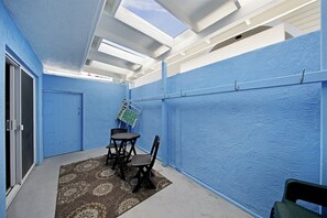 Un petit patio clos, avec des murs bleus, une porte, une table avec des chaises et un tapis à motifs.