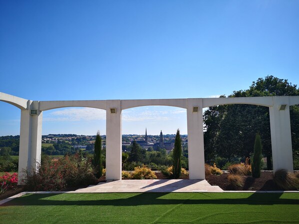 Surrounded by lush gardens and a distant view of the town, this serene outdoor space offers a tranquil atmosphere.