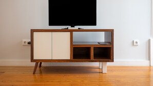 Ein HolztV-Schrank mit einem flachbildfernseher darüber, eine Vitrine und ein Regal.