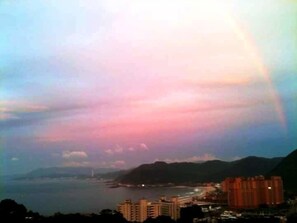 A coastal cityscape with buildings and a mountain range in the background.