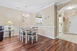 A dining area with a wooden table and chairs, a lamp, and a chandelier.