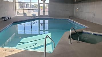 An indoor swimming pool with clear water, a diving board, and a small adjacent pool.