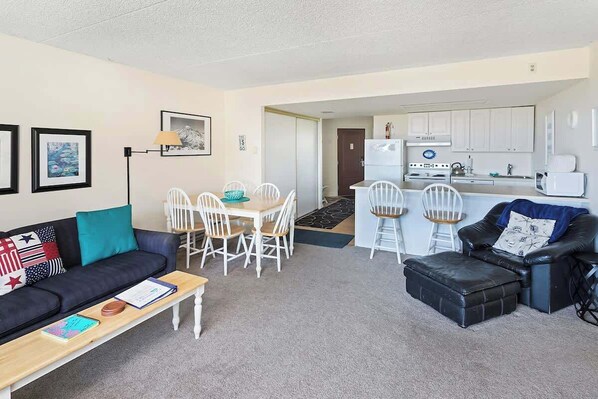 A compact living space with a sofa, dining table, chairs, kitchenette, and a small coffee table. - Gearhart House G600 (Gearhart)