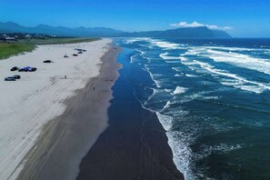 A beach with a long stretch of sand, waves crashing onto the shore, and a clear sky. - Gearhart House G600 (Gearhart)