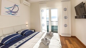 A bedroom with a bed, a nightstand, a wall-mounted air conditioner, and a window with curtains.