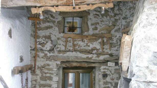 A rustic stone interior with a wooden-framed window, a hanging light fixture, and a stone wall. - Cozy Cottage with Jacuzzi for 8/10 people.  (Navalosa)