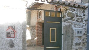 A rustic stone building with a dark green door featuring gold accents. A sign on the wall reads "casa rural." - Cozy Cottage with Jacuzzi for 8/10 people.  (Navalosa)