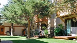 Une maison avec une façade en pierre, une terrasse en bois et une pelouse bien entretenue.