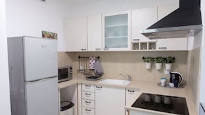 Eine kleine Küche mit Kühlschrank, Mikrowelle, Spüle und Herd.