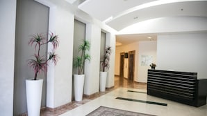 Eine moderne Lobby mit einer Rezeption, Blumentöpfen und einem gemusterten Teppich.