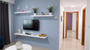 Ein modernes Wohnzimmer mit einem Flachbildfernseher, weißen Regalen und Dekorationselementen.