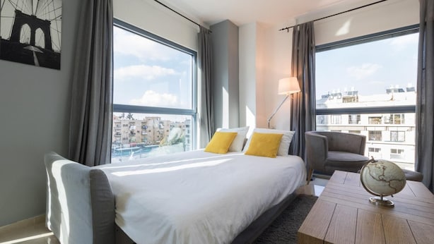 Ein Hotelzimmer mit einem großen Bett, einem Schreibtisch und Blick auf die Stadt.