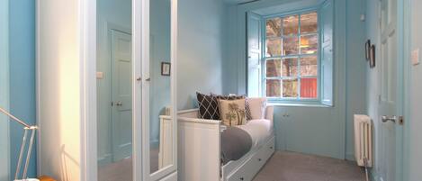 A bedroom with a bed, wardrobe, and window.
