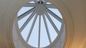 Une lucarne circulaire dotée d’un cadre décoratif et d’un pilier central.