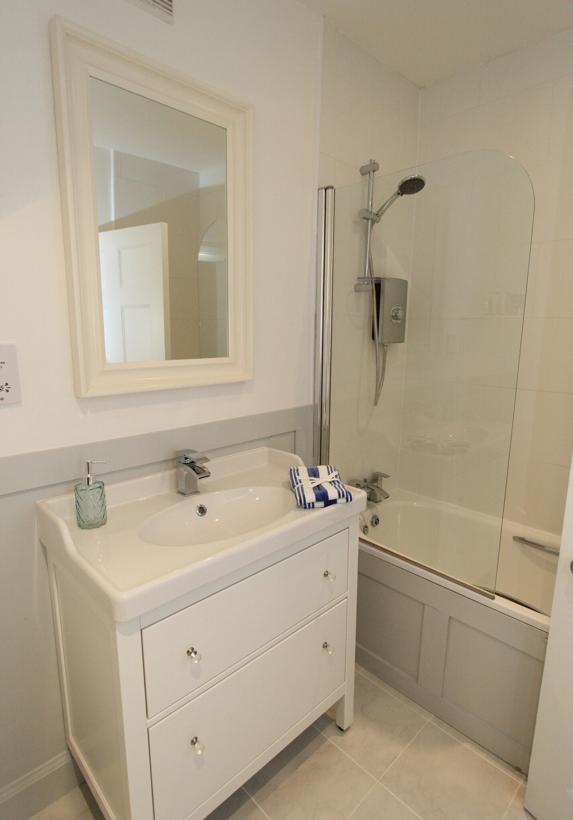 Une salle de bain avec un lavabo blanc, un miroir et une douche.
