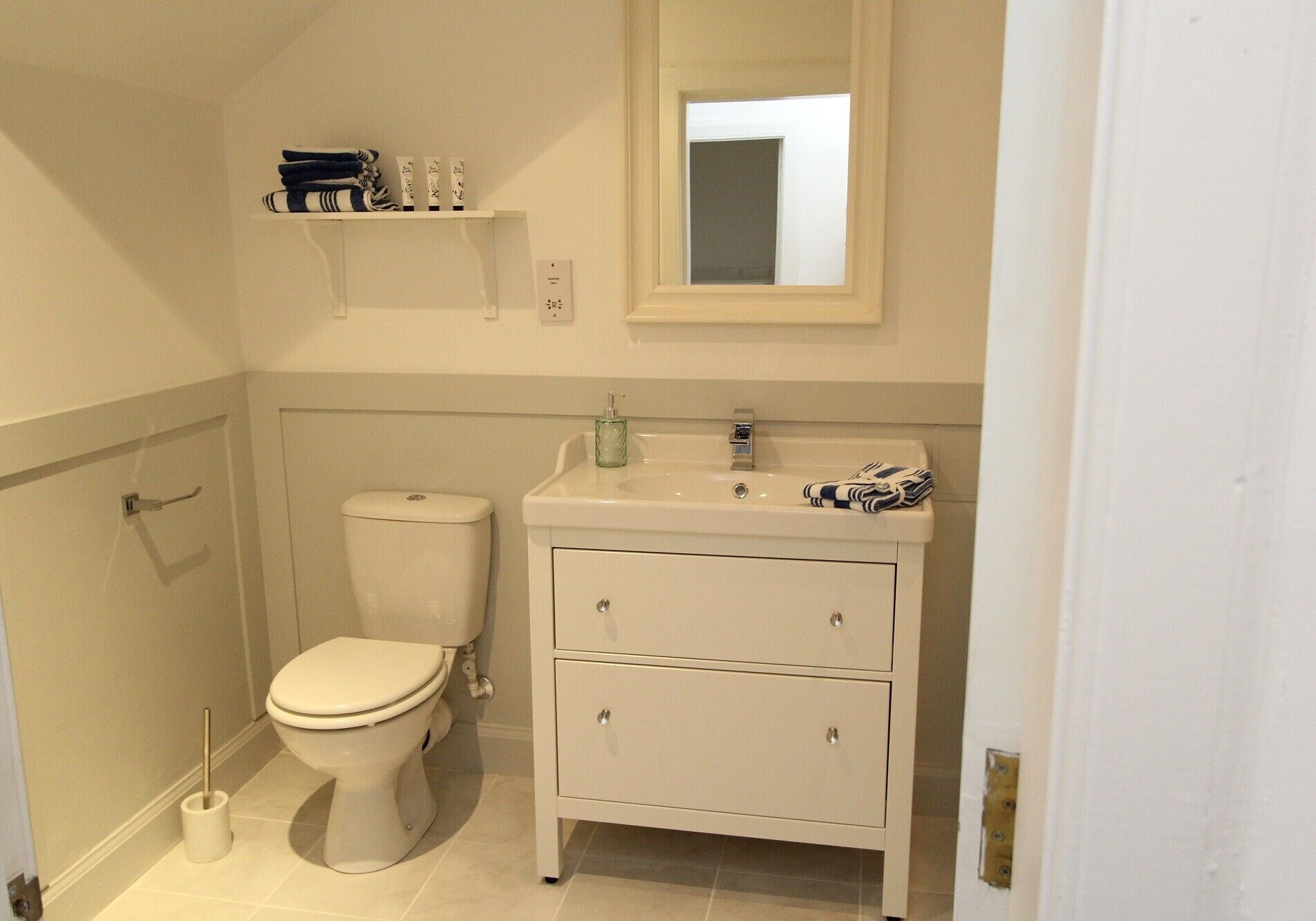 Ein kleines, sauberes Badezimmer mit Toilette, Waschbecken und Spiegel.