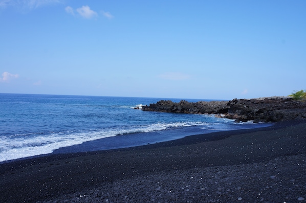 Una playa con guijarros oscuros y un litoral rocoso.