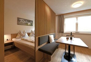 Ein Zimmer mit einem Bett, einer Bank, einem Tisch und einem Fenster.