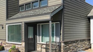 A modern two-story house with a stone foundation, large windows, and a front porch with a bench. - Charming Home - 1 Mi to Yellowstone National Park! (West Yellowstone)