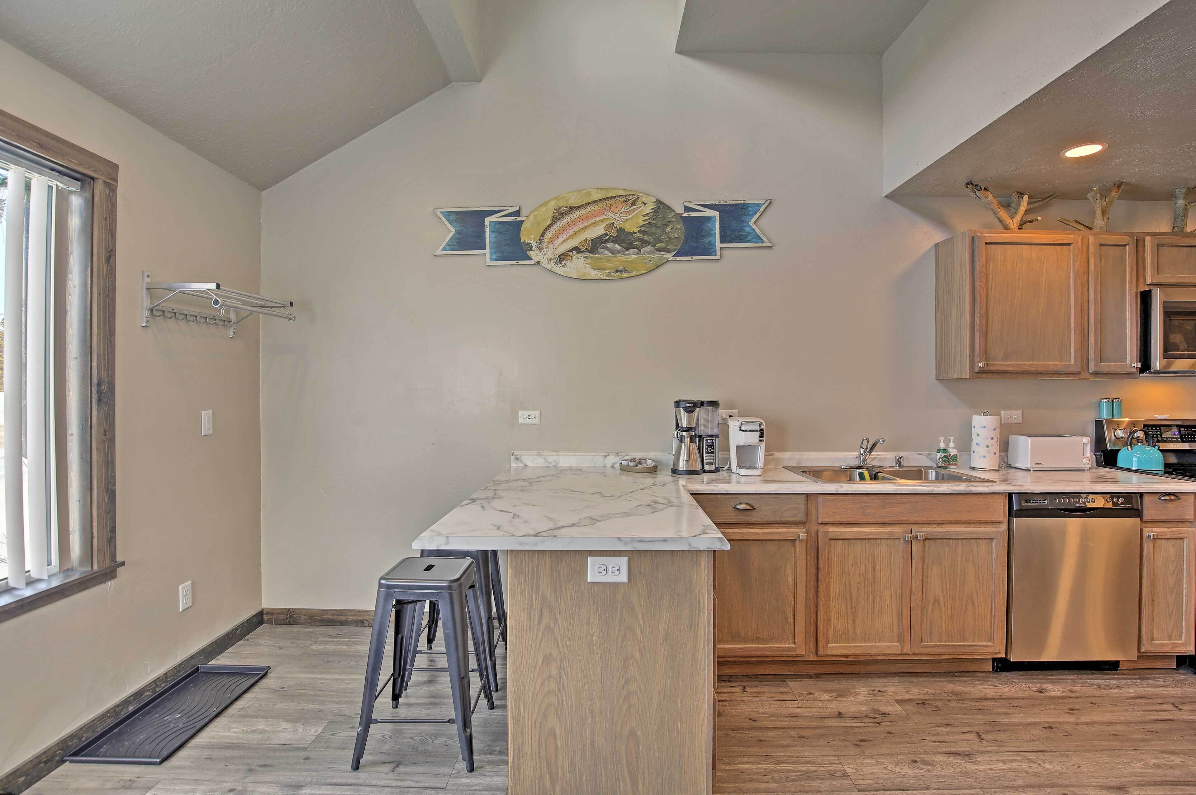 A modern kitchen with wooden cabinets, a marble countertop, and a built-in dishwasher.