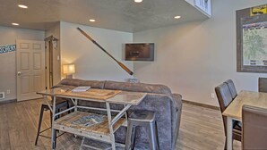 A cozy living area with a sofa, a coffee table, and a TV mounted on the wall. - Charming Home - 1 Mi to Yellowstone National Park! (West Yellowstone)